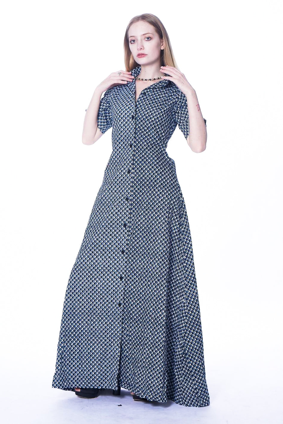 Photo of a woman wearing myObioma's maxi and button-down dress Grey Agege. The soft and comfortable fabric features gorgeous grey patterns scaled to feel like a lavish texture. The collared dress also includes medium-length sleeves for a fancy flair.