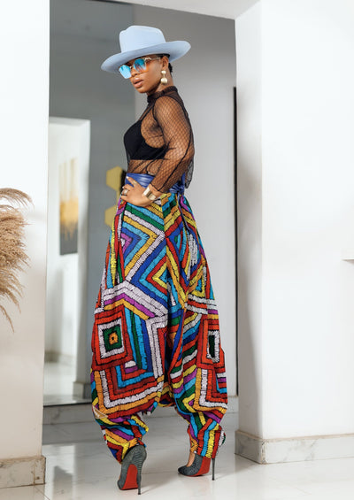 A woman posing in multicolored african print parachute pants.