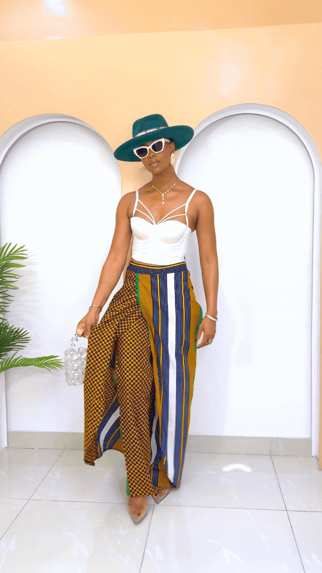 Model wearing a vibrant, multi-colored African Ankara pants and skirt with intricate patterns, featuring an elastic waistband and zipper closure.