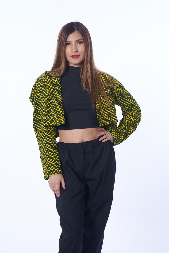 Photo of a woman wearing myObioma's Azu Crop Top Blazer, which features a yellow and black pattern scheme. The loose shoulders and sleeves make a comfortable fit while generating an impressive aura. 