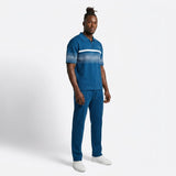 Model wearing the Anioma blue men’s athleisure set with a short-sleeve knit zip polo, geometric stripe detailing and relaxed straight-cut drawstring pants.
