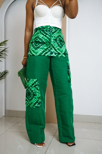 Person wearing a white top and green patterned pants against a white background