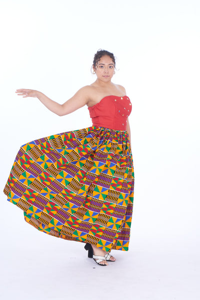 Photo of a woman wearing myObioma's Efua Kente Skirt, which is a voluminous a-line skirt designed with African fabric. The skirt is long and high-waisted while filled with playful and multicolor geometric patterns. 