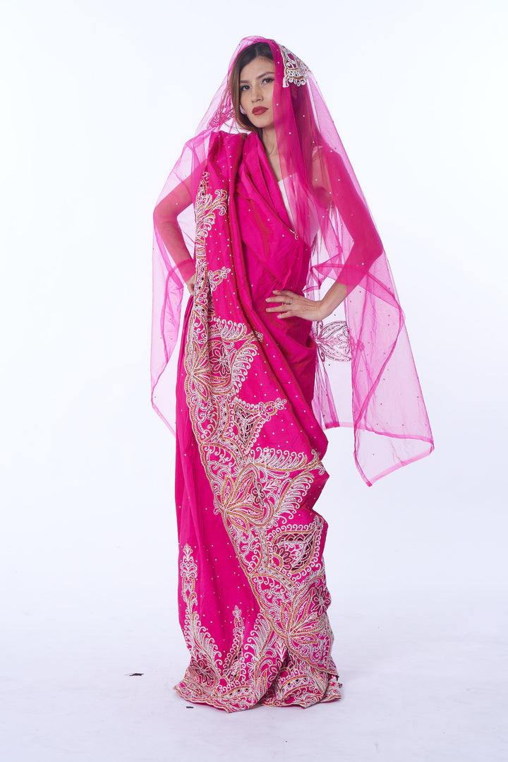 Photo of a woman wearing myObioma's Nafrican Pink Hijab Dress, which is long and includes glittery geometric design patterns around the hem and across the dress. It also features a matching pink sheer hijab that reaches below the waist. 