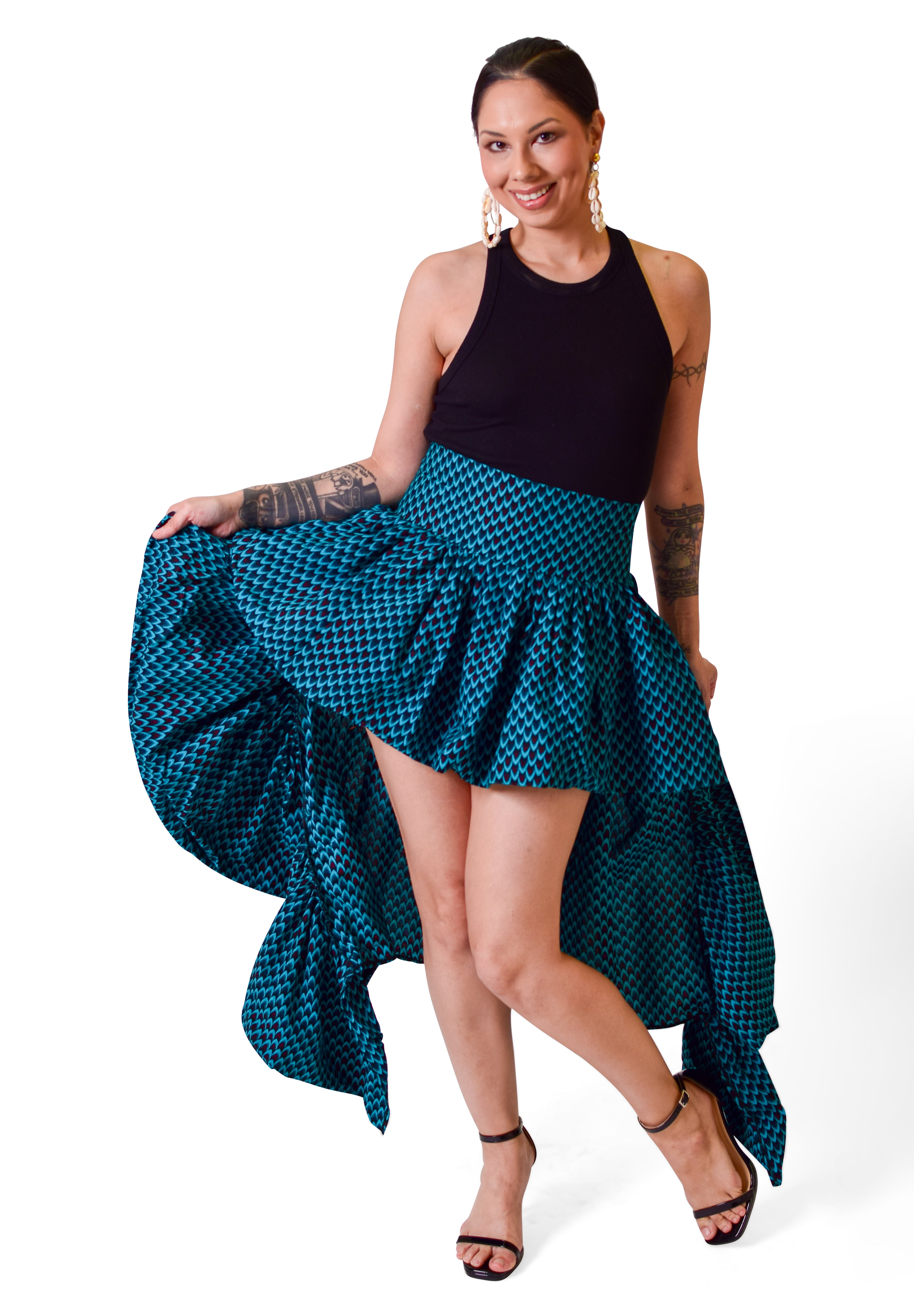 Model wearing Nkukwaya high-low tiered Ankara skirt in teal and black, styled with black top and boots, hand-crafted in Africa