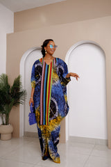 Woman wearing Onwenkem Adire Bubu dress with colorful Adire print and bold Aso Oke panel down the front, styled with blue sunglasses and clutch.