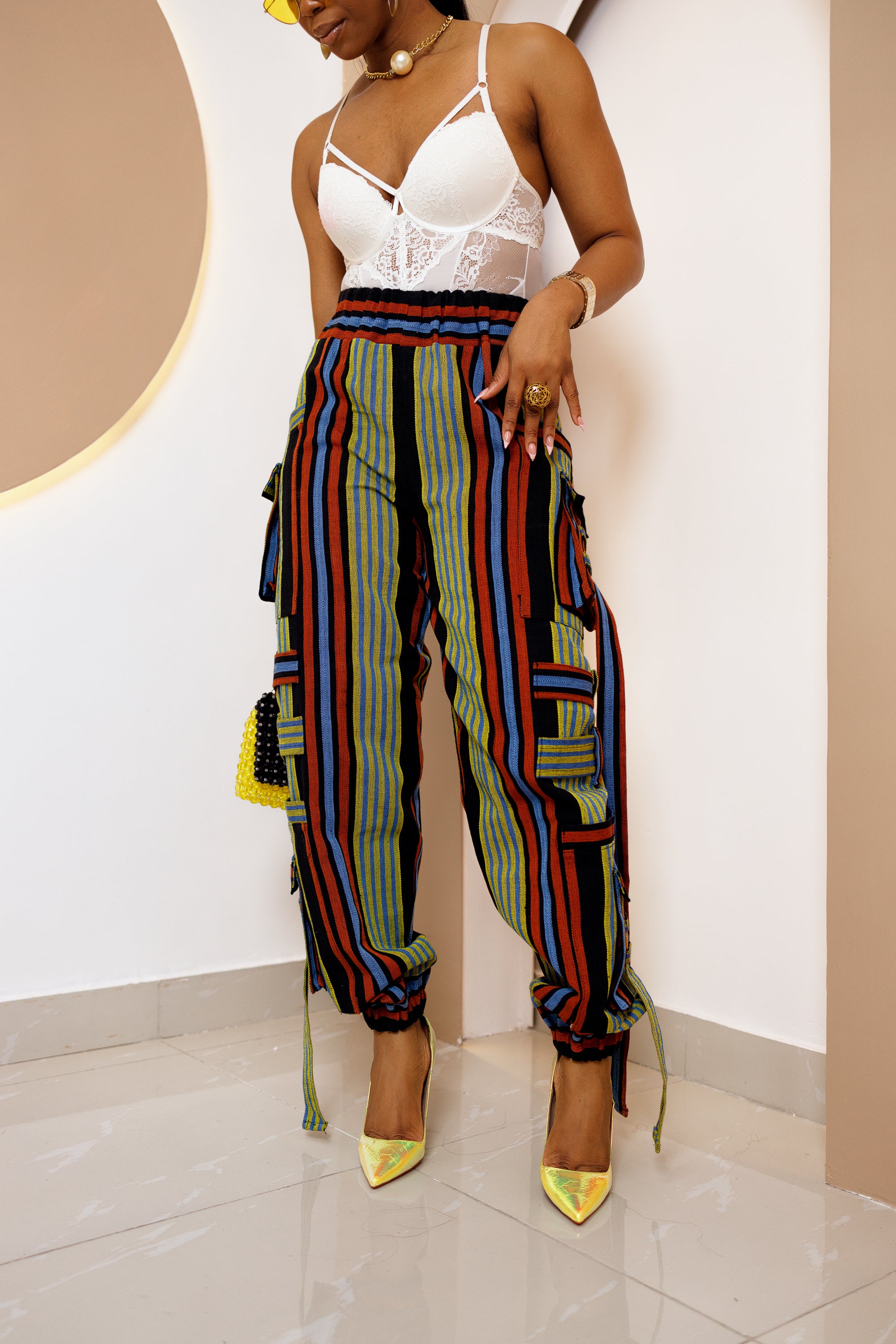 A person wearing high-waisted cargo pants with a colorful geometric African Aso oke pattern.