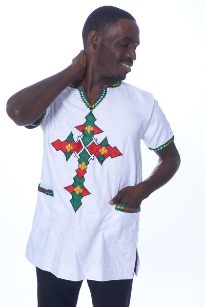 Photo of a man wearing myObioma's Menelik Ethiopian Shirt, which is white with multicolor geometric patterns in the shape of a T down the chest. The shirt is v-neck style and includes patch pockets. 