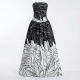 A strapless floor-length gown with a black and white floral line-art print, featuring a fitted bodice and a voluminous skirt, shown against a plain white studio background.