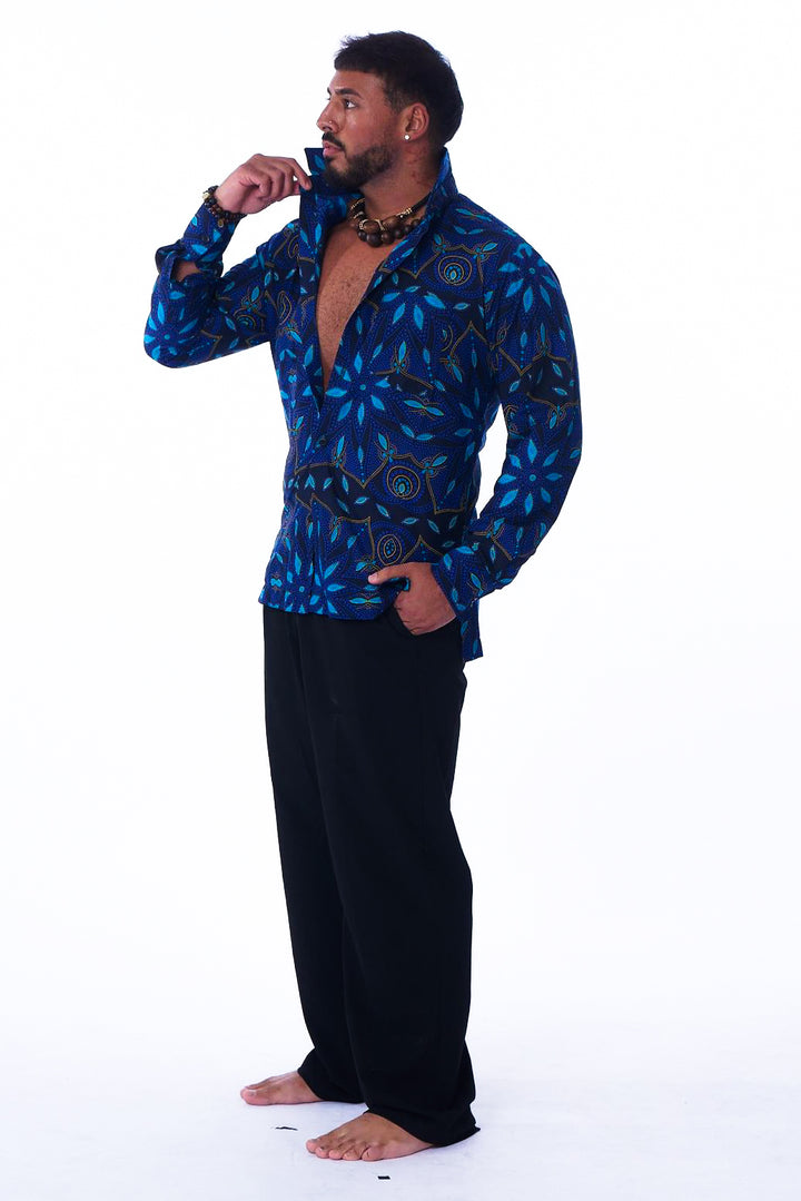 Photo of a man wearing myObioma's blue Modern West African Dress Shirt. It features deep blue geometric patterns with gold accents and a loose collar, which all fit comfortably over the silhouette.