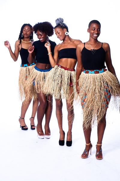 Photo of four women wearing myObioma's high-waisted Grass Dancing Skirts. They feature colorful underskirts with beautiful red and blue patterns for comfort and protection.