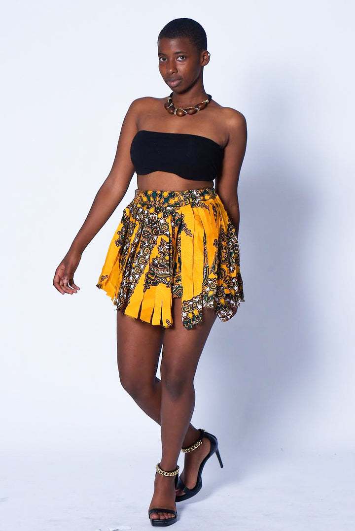 Photo of a woman wearing myObioma's yellow and high-waisted Dashiki Dancing Skirt with Frills. The dancing skirt with white and gold accented frills is printed with comfortable material for exaggerated movements. 