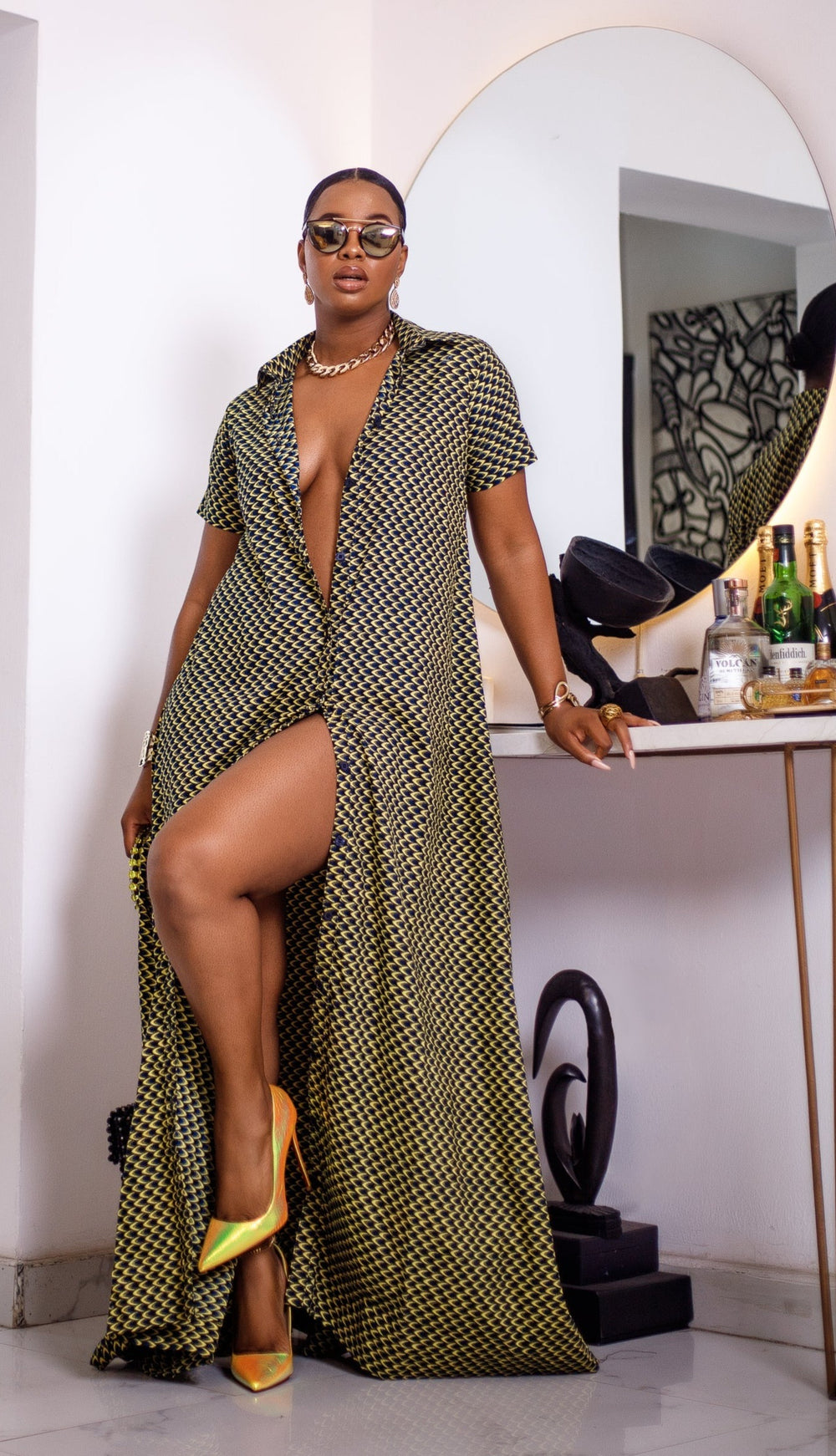 A woman posing in a short sleeve African print maxi dress shown in black and yellow.