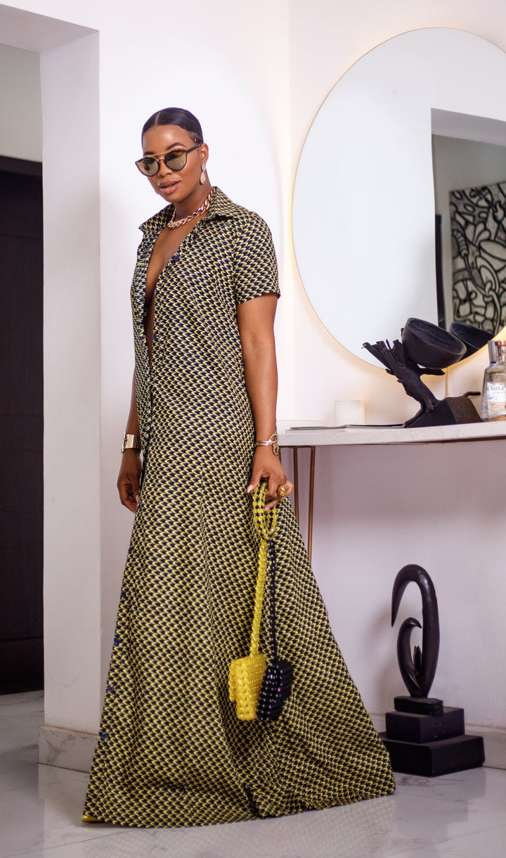 A woman posing in a short sleeve African print maxi dress shown in black and yellow.