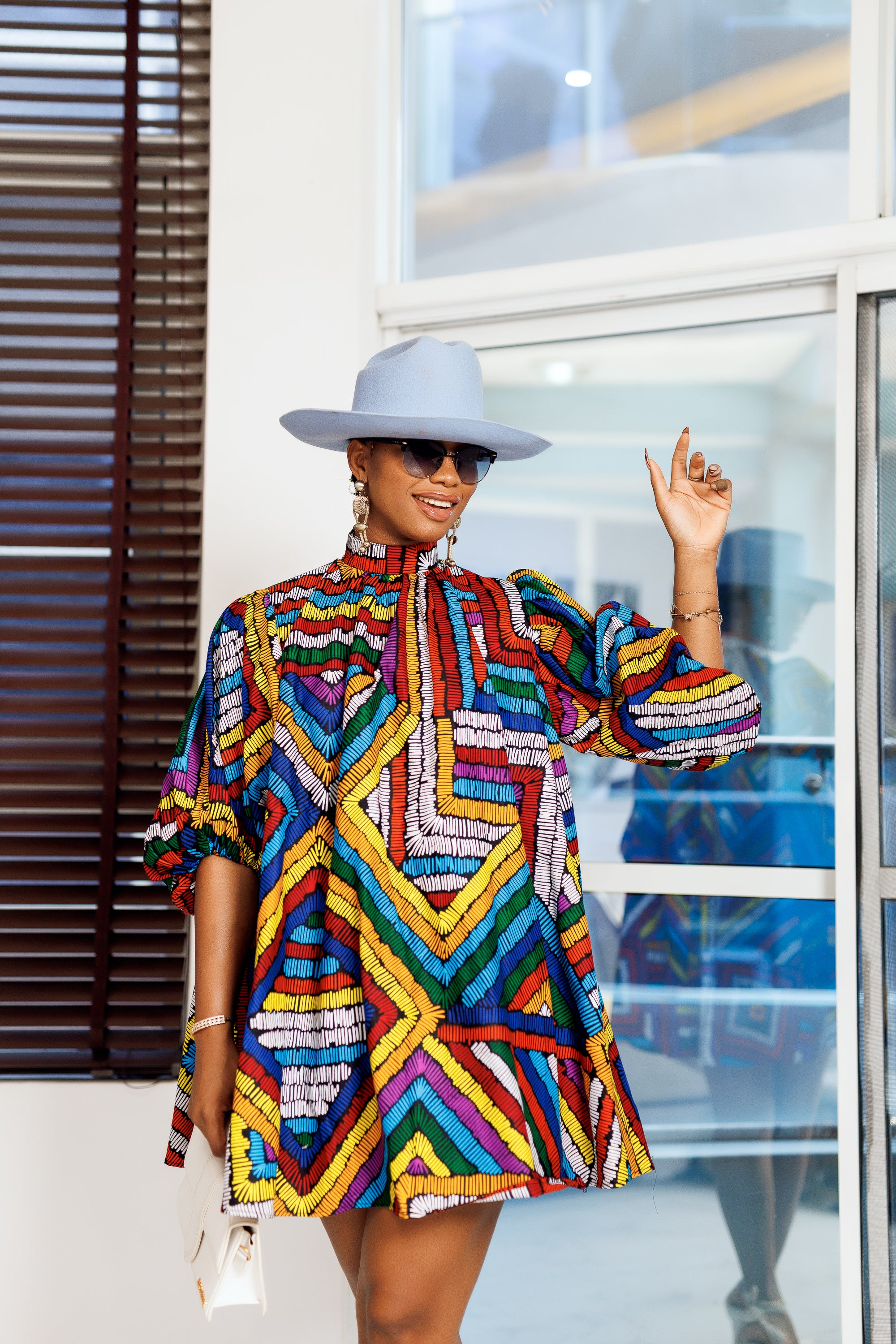 A woman posing in a multicolored African print mini dress.