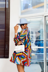 A woman posing in a multicolored African print mini dress.