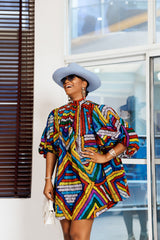 A woman posing in a multicolored African print mini dress.