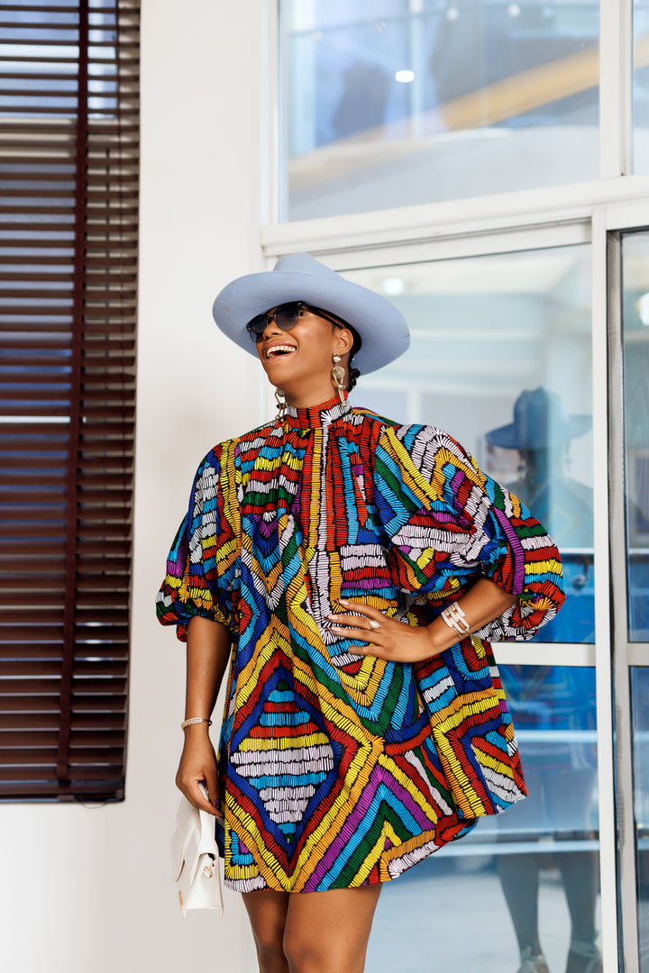 A woman posing in a multicolored African print mini dress.