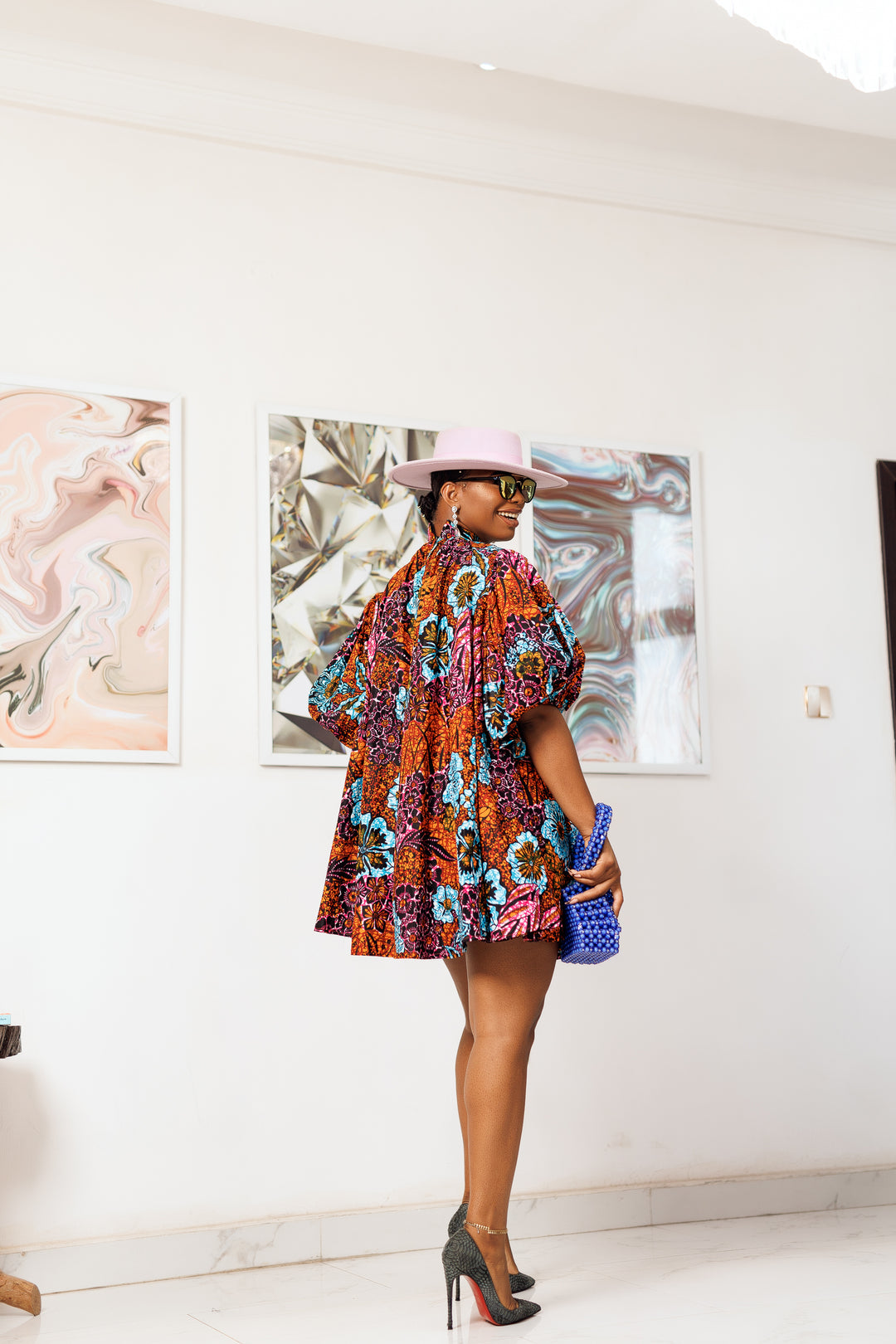 A woman posing in a multicolored African print mini dress.