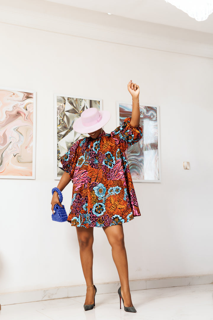 A woman posing in a multicolored African print mini dress.