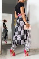 A woman posing in black and white African Print parachute pants.