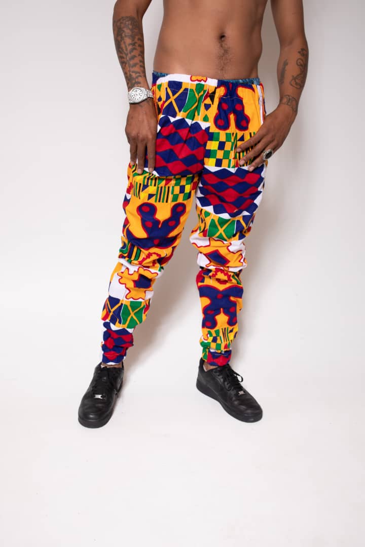 Red, yellow, green, and blue geometric patterned jogger pants with elastic waistband, cinched ankles, and slanted pockets.