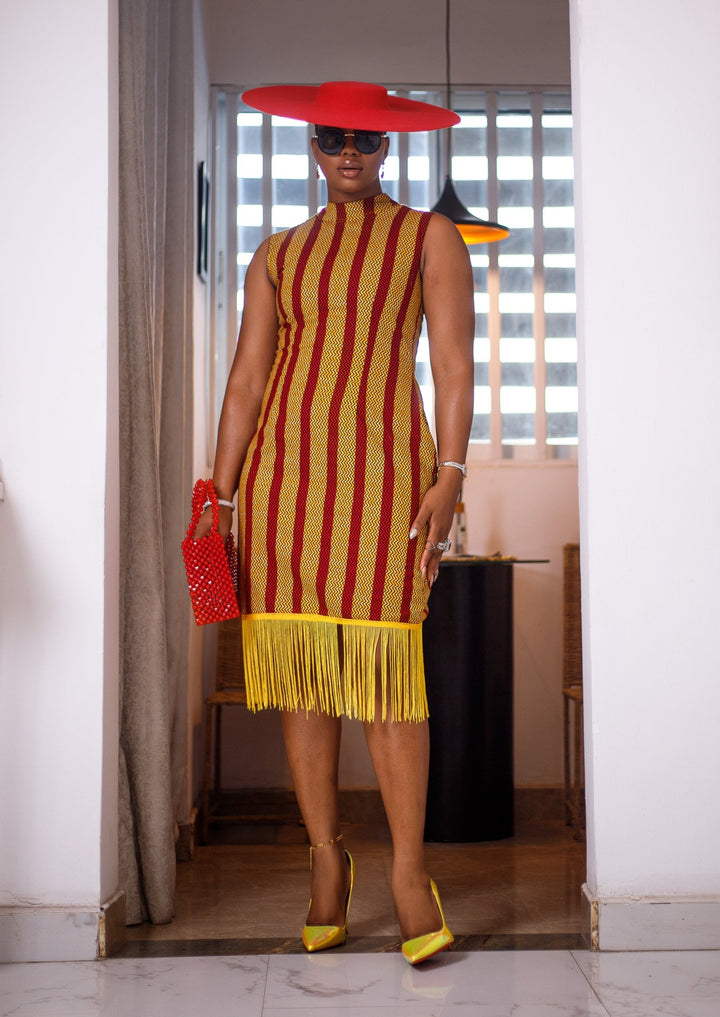 A woman posing in a red and yellow African Ankara print midi dress with frills at the bottom.