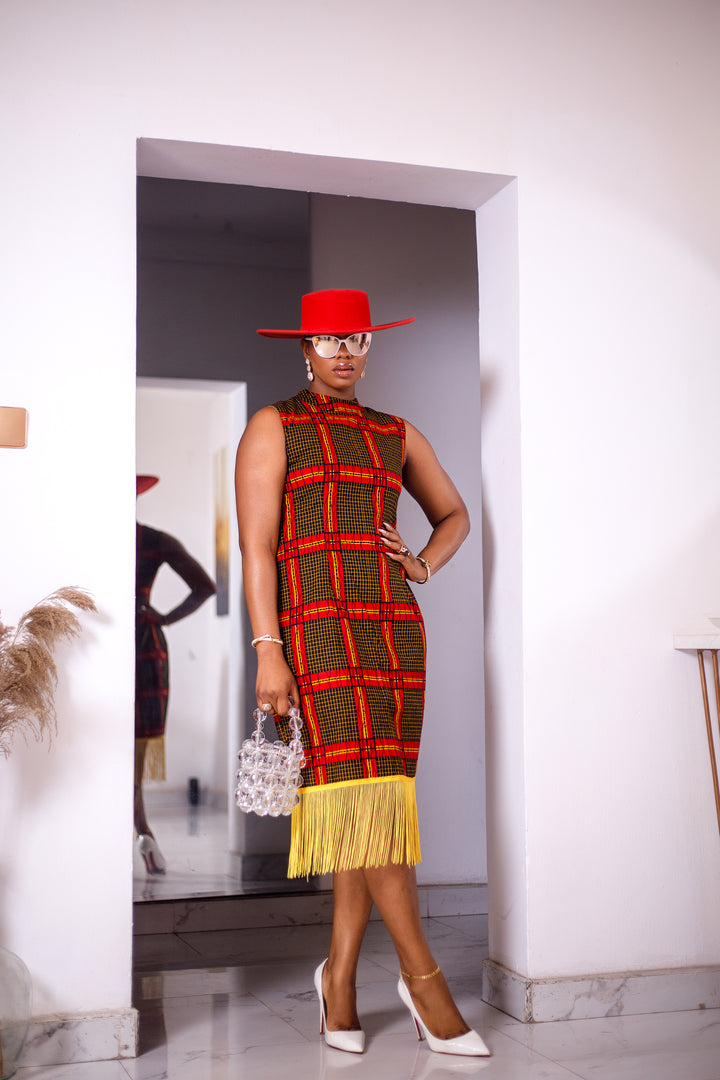 A woman posing in a red and yellow African Ankara print midi dress with frills at the bottom.