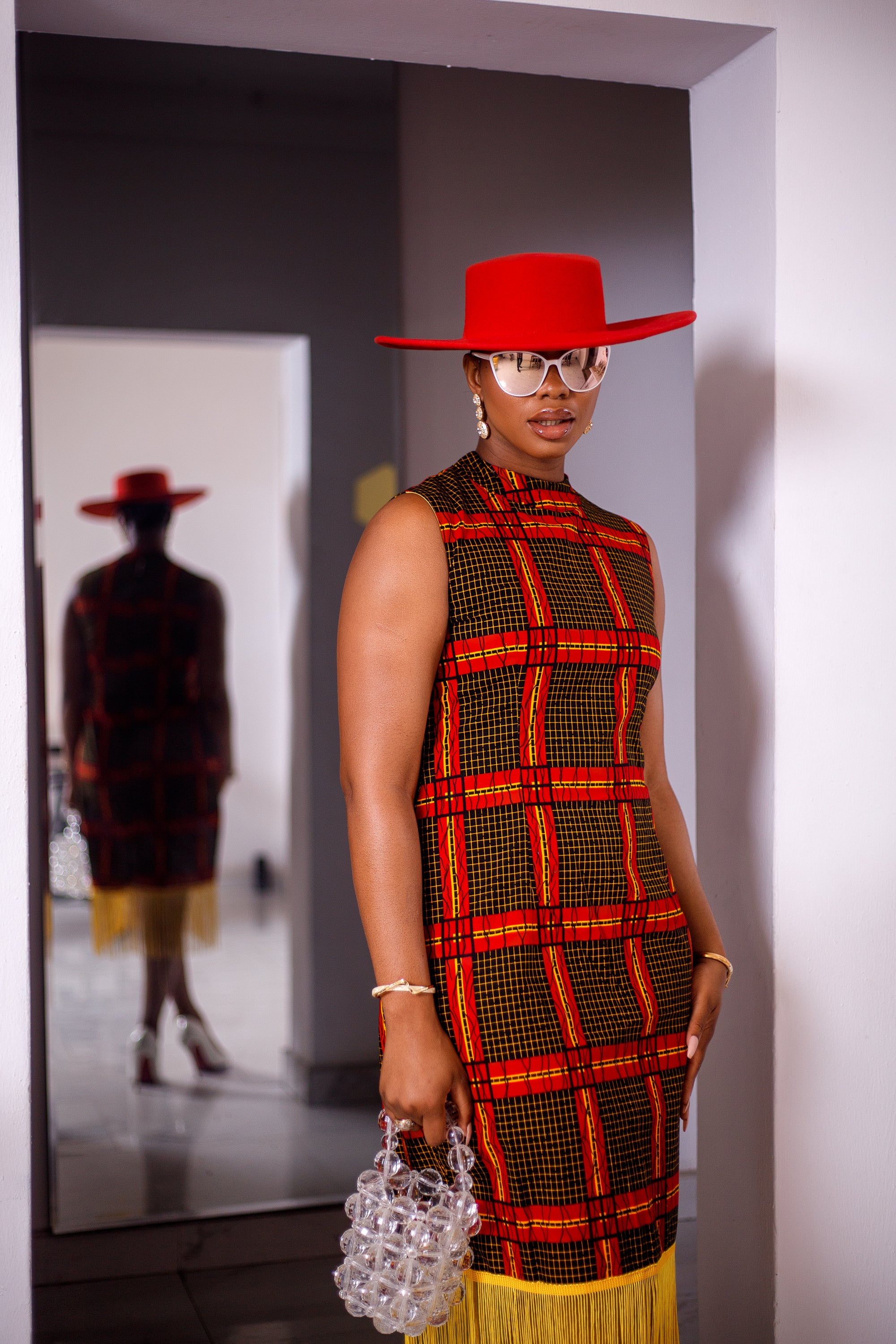 A woman posing in a red and yellow African Ankara print midi dress with frills at the bottom.