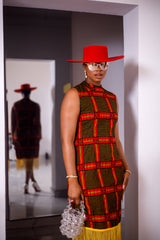 A woman posing in a red and yellow African Ankara print midi dress with frills at the bottom.