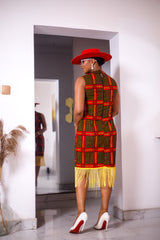 A woman posing in a red and yellow African Ankara print midi dress with frills at the bottom.