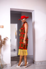 A woman posing in a red and yellow African Ankara print midi dress with frills at the bottom.
