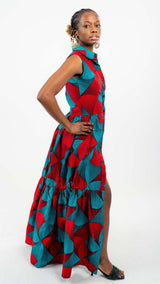 Red and blue patterned dress. Dress is sleeveless and collared, with a trumpet style silhouette and side leg slit.