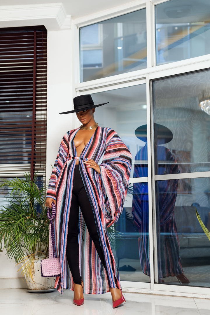 A woman posing in a multicolored chiffon fabric African kimono.