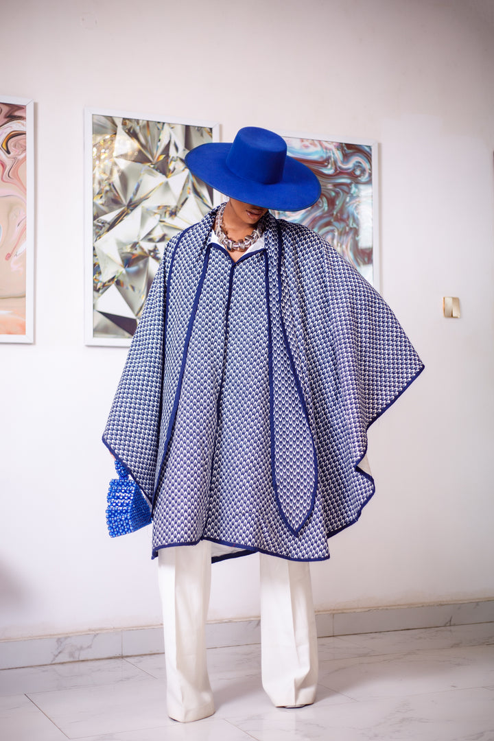 A woman posing in a blue and white African Print cape.
