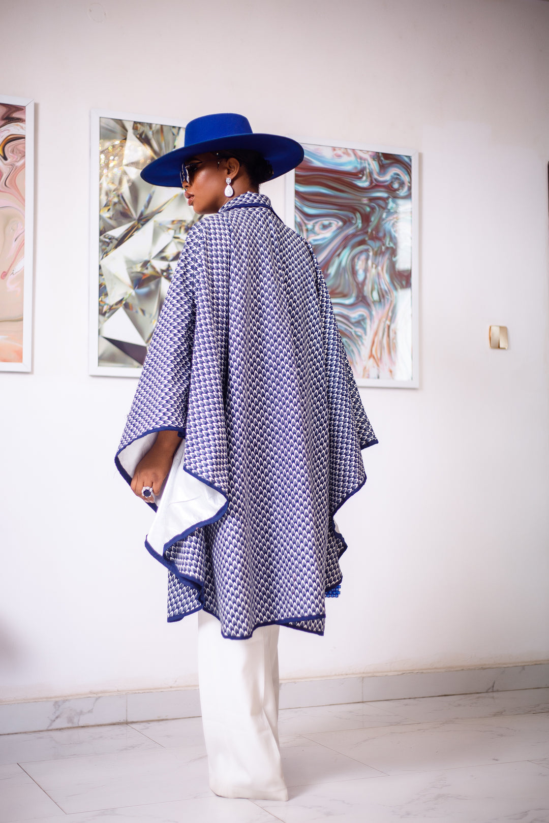 A woman posing in a blue and white African Print cape.