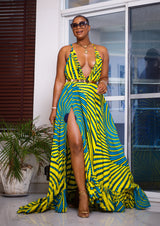 Woman posing in a yellow and blue spiral pattern summer dress. The maxi dress is designed with thin straps, a deep v neckline, and a flattering slit down the right leg.