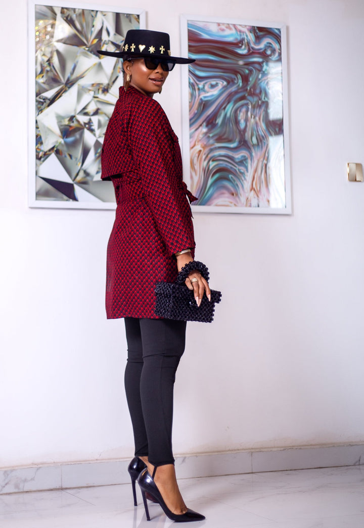 A woman posing in a black and red African print trench coat.