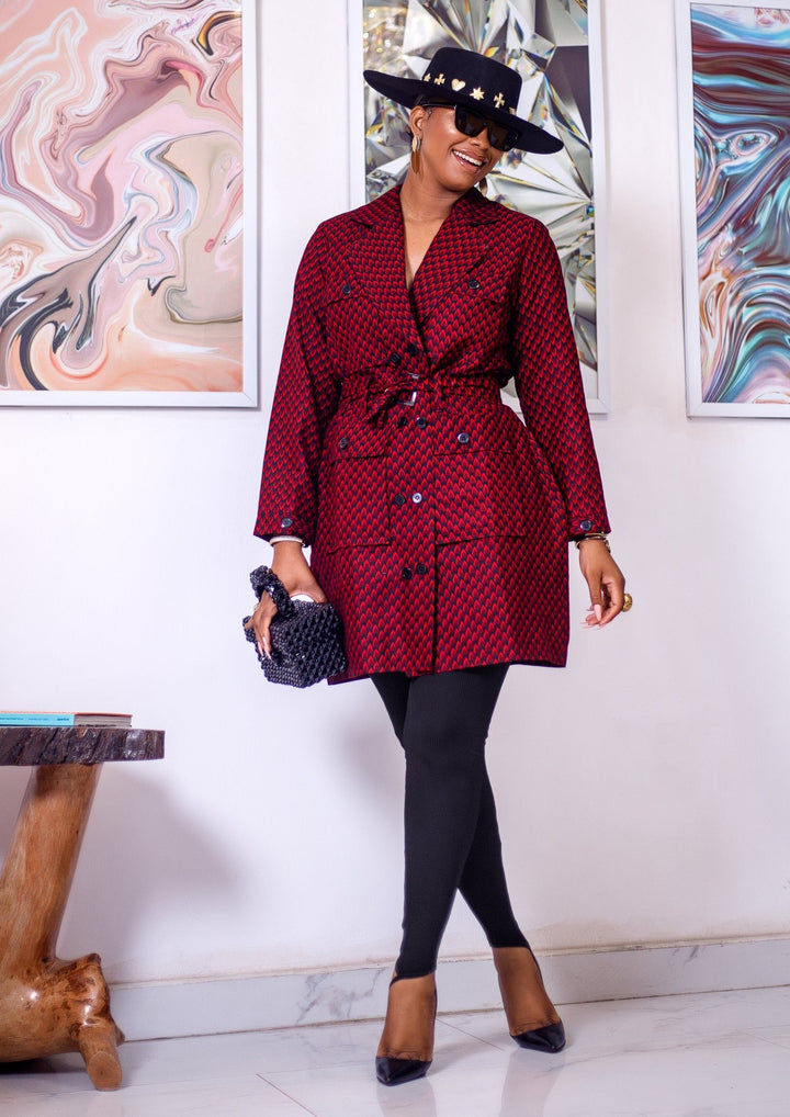 A woman posing in a black and red African print trench coat.