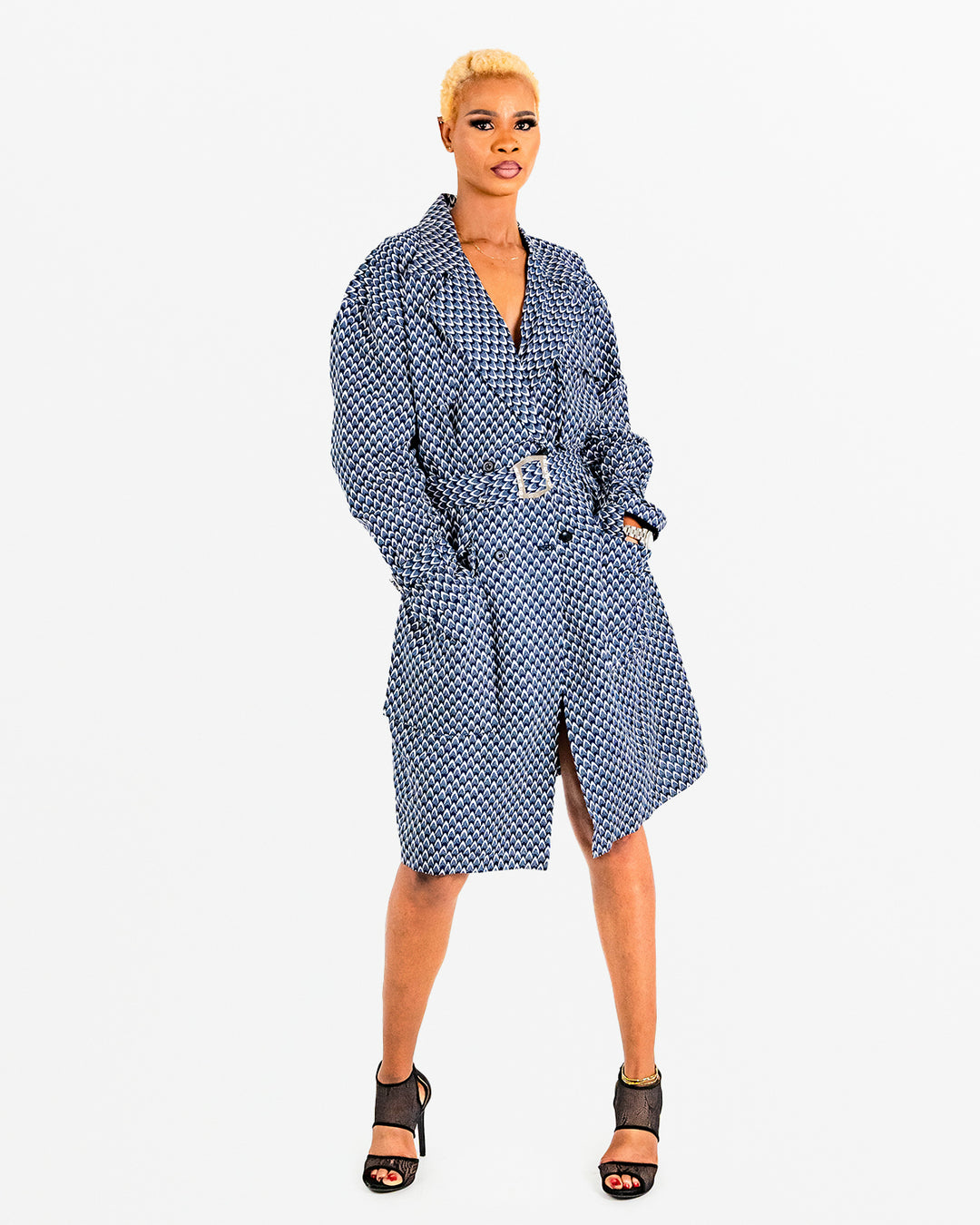 A woman posing in a blue and black African print trench coat.