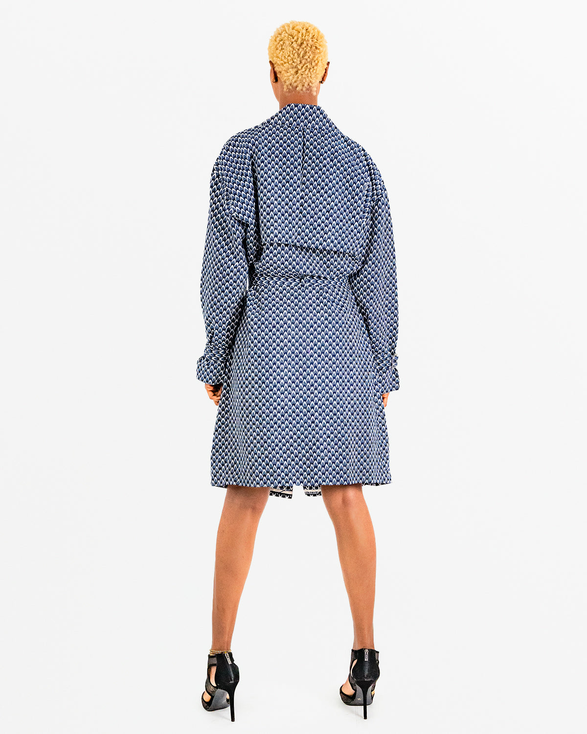 A woman posing in a blue and black African print trench coat.