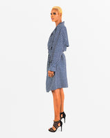 A woman posing in a blue and black African print trench coat.