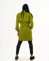 A man posing in a yellow and black African print trench coat.