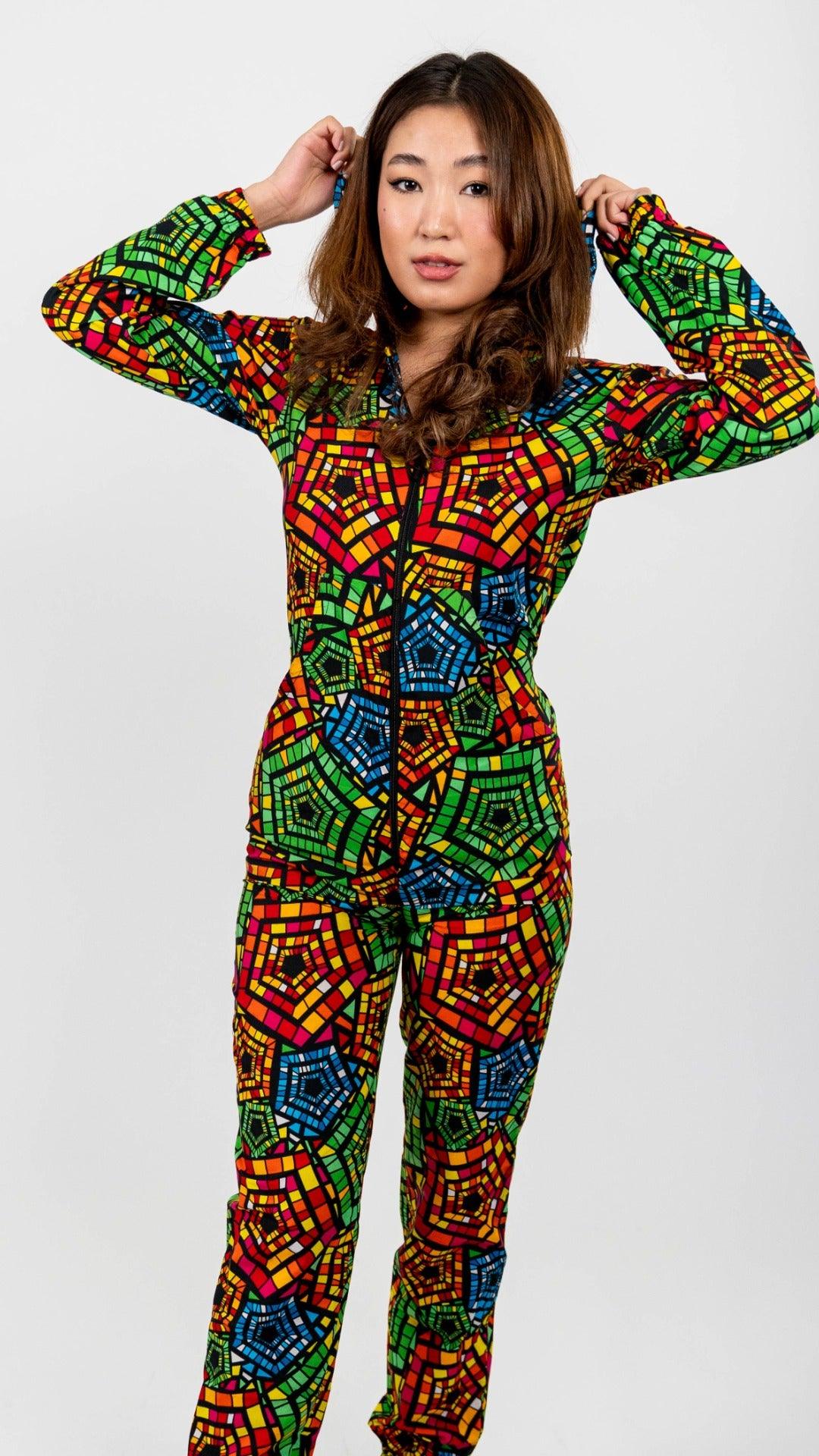 Green, red, and blue patterned full body onesie. Onesie is long sleeved and hooded, with a black front zipper and elastic ankle bands.