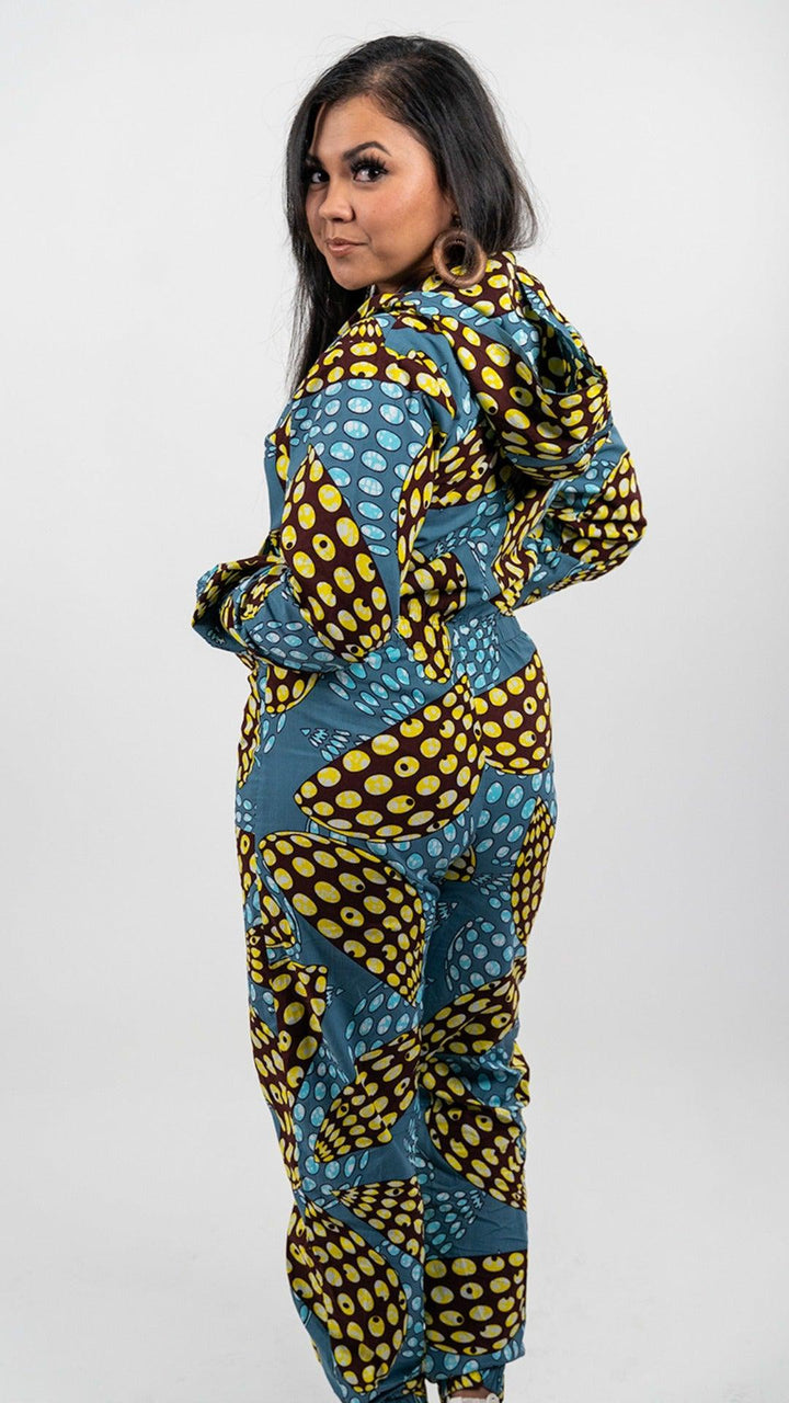 Yellow, blue, and black patterned full body onesie. Onesie is long sleeved and hooded, with a black front zipper and elastic ankle bands.