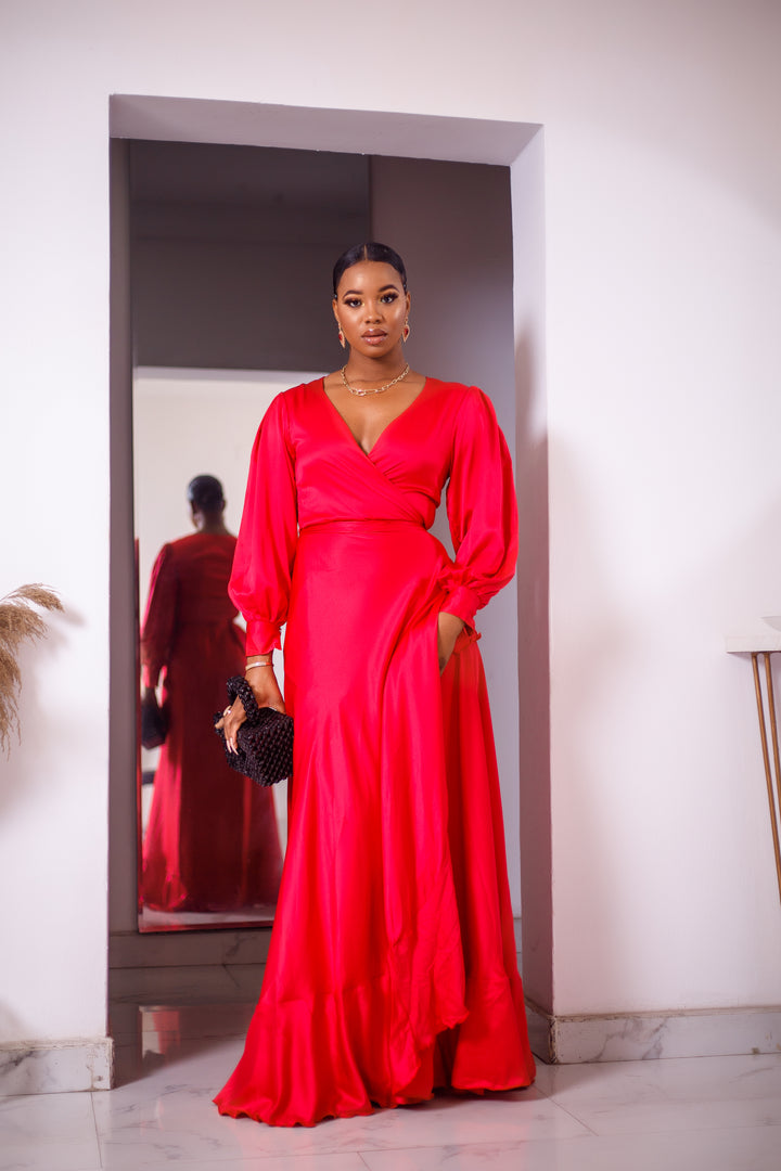 A woman posing in a red maxi dress with ruffles.