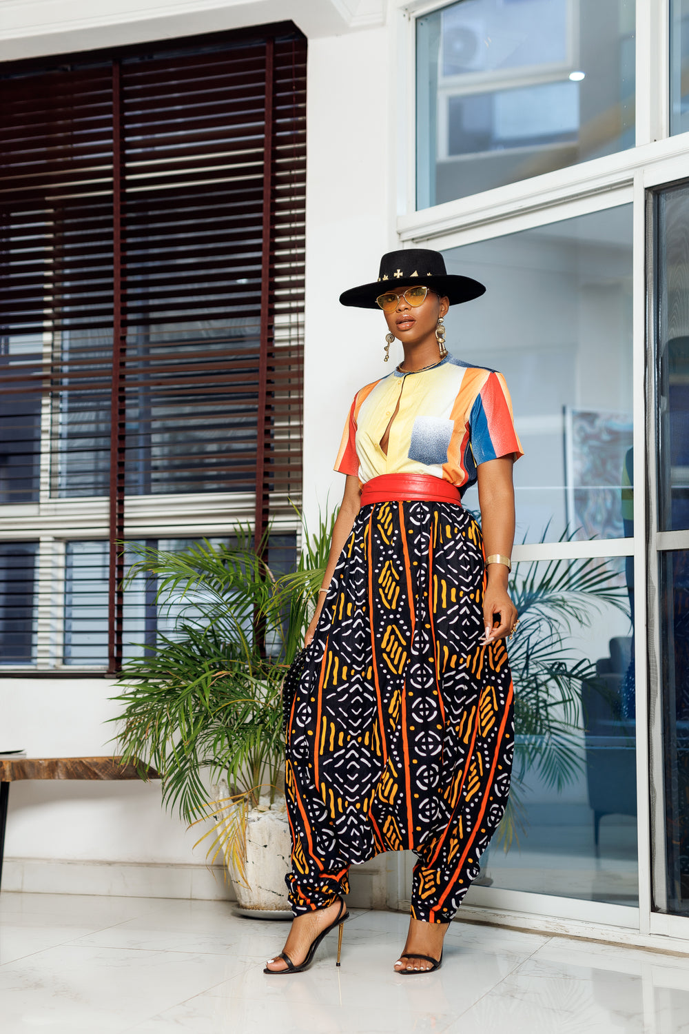 A woman posing in multicolored African Print parachute pants.