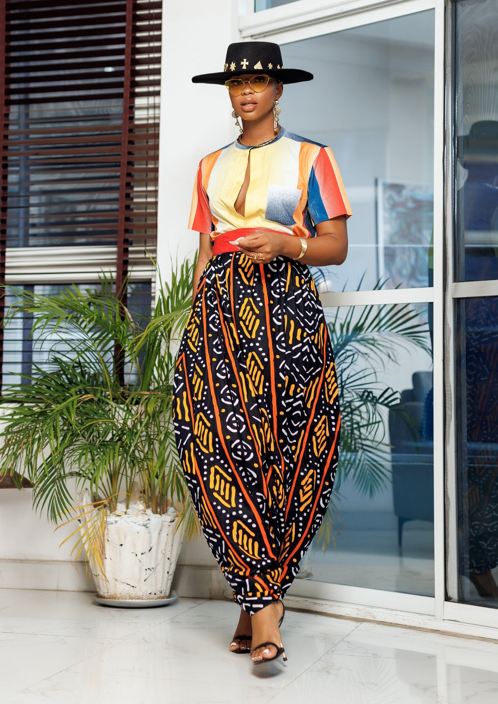 A woman posing in multicolored African Print parachute pants.