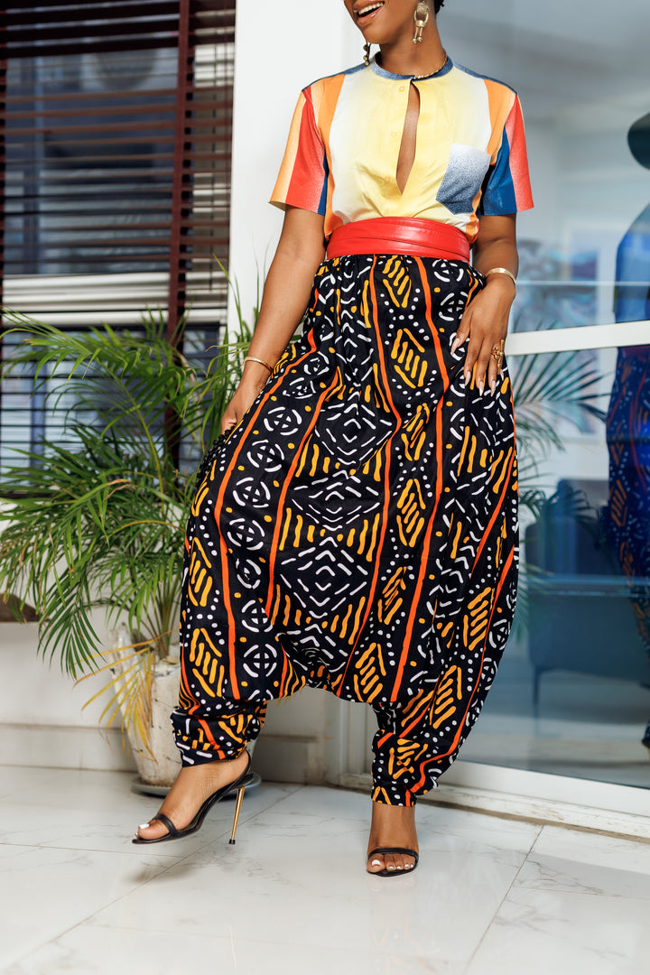A woman posing in multicolored African Print parachute pants.