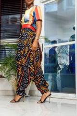 A woman posing in multicolored African Print parachute pants.